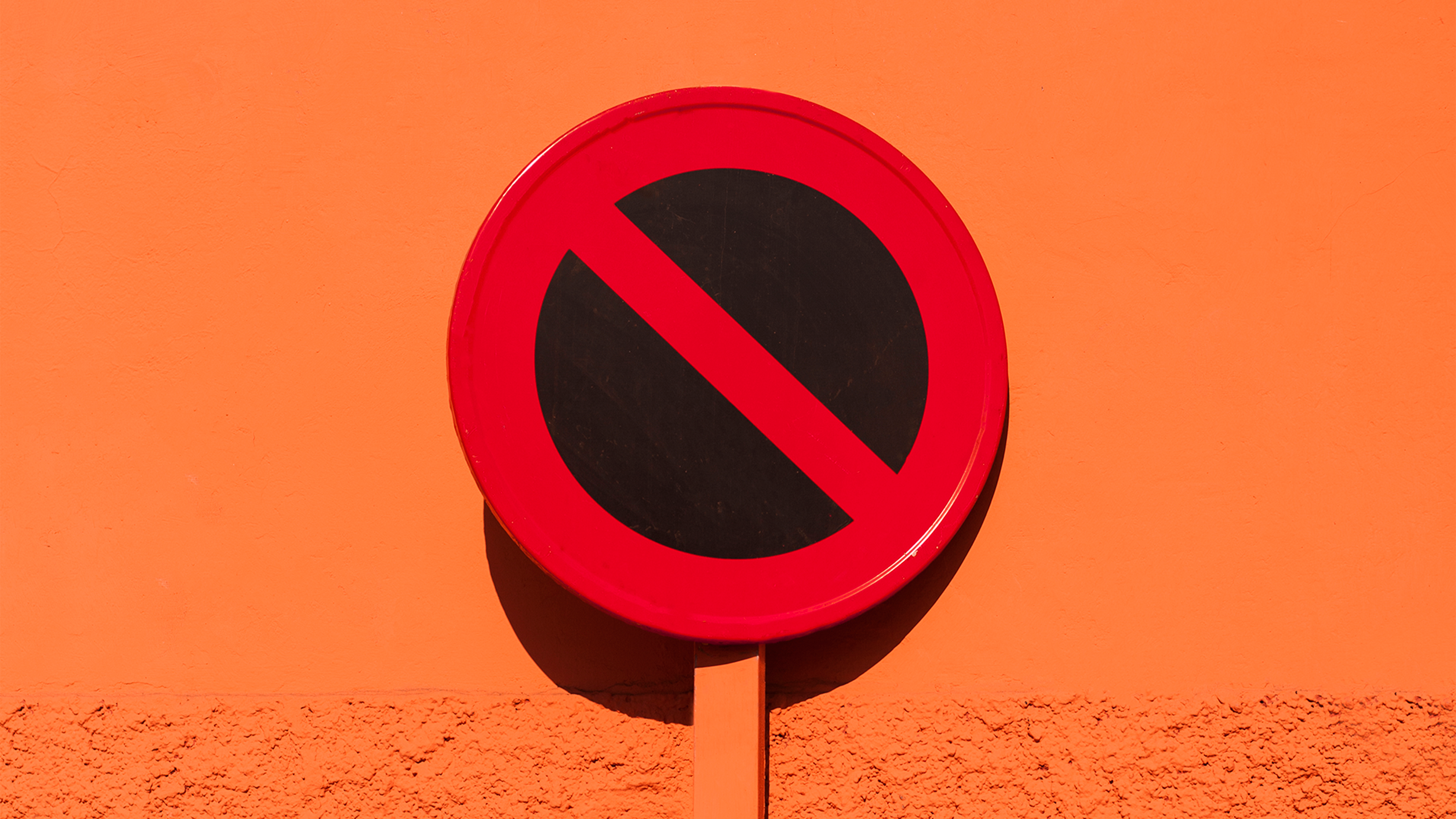 A stop road sign on an orange background. 