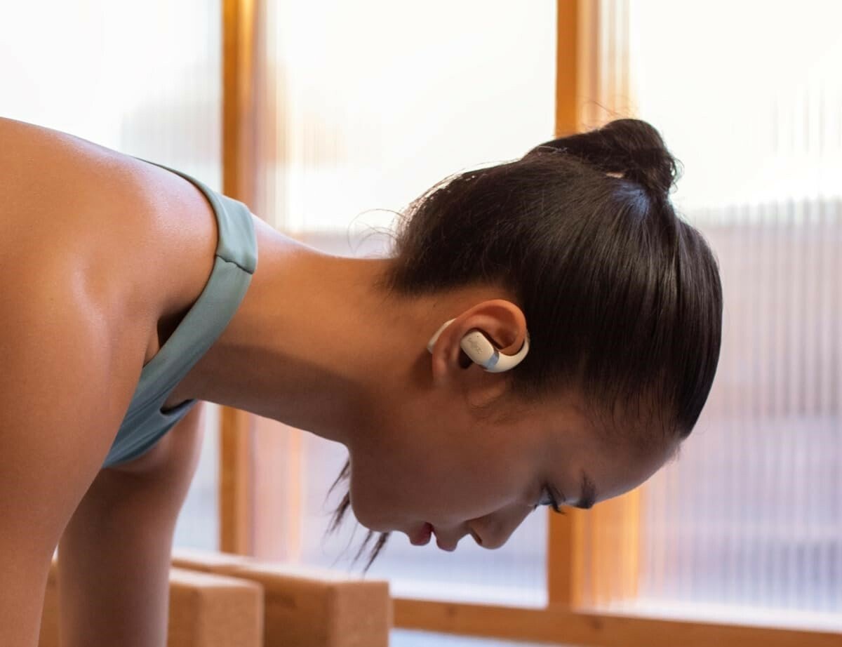 a person holds a plank workout position while wearing the shokz openfit earbuds