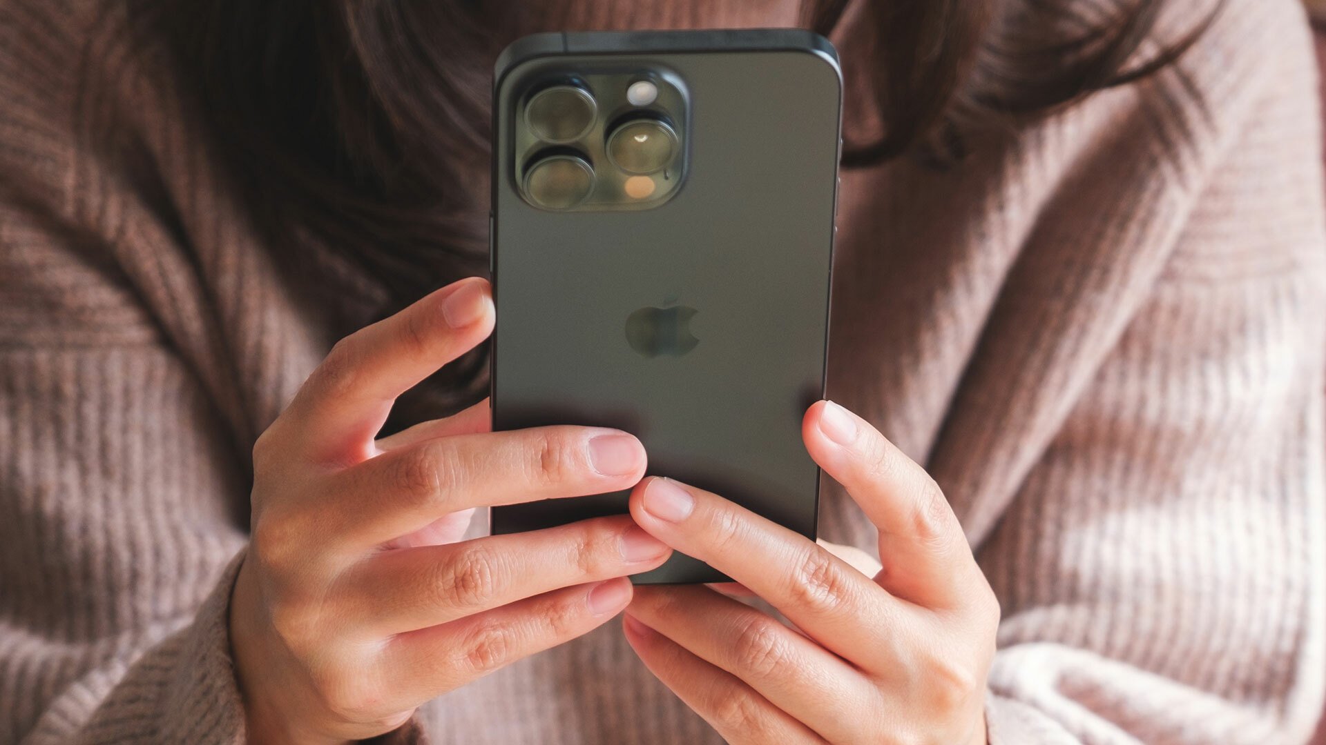 A close-up of a woman holding an iPhone.