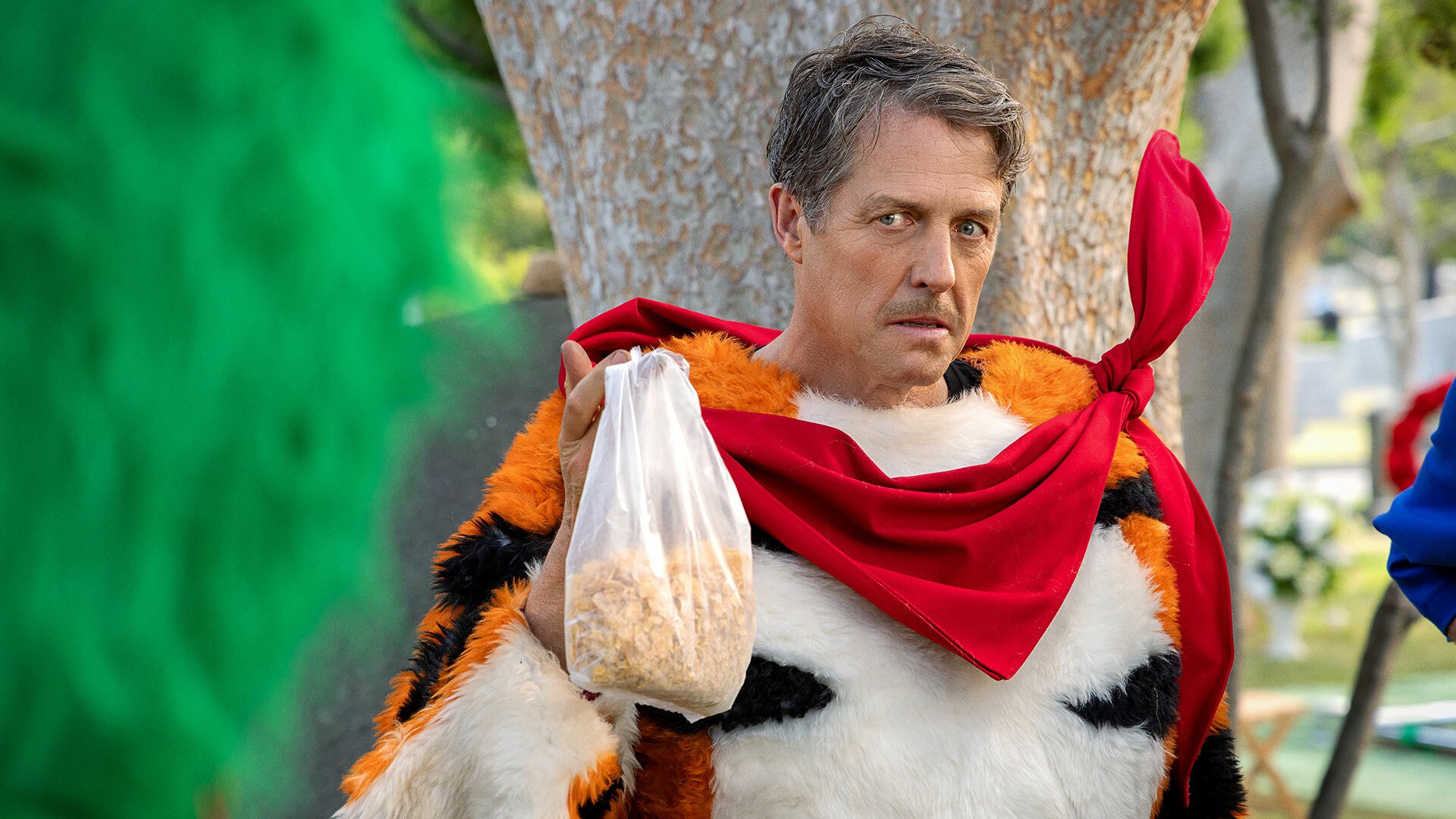 A man in a tiger costume looks angry while holding up a bag of cereal.
